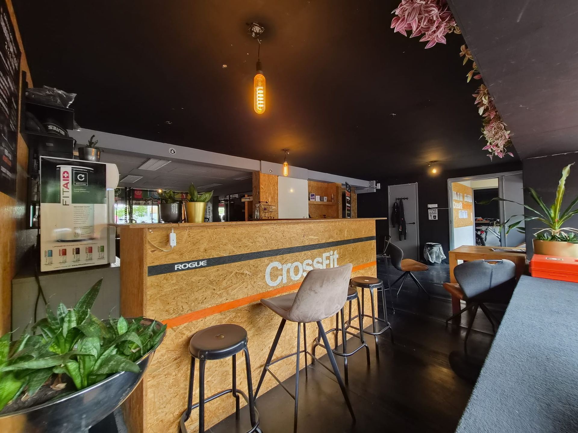 De bar in de box van CrossFit Gorinchem met hout, planten en CrossFit-logo